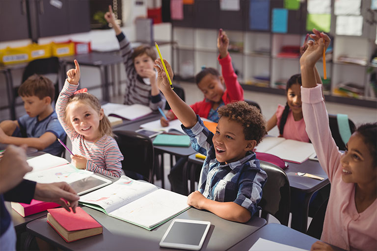 Students raising their hands in a classroom