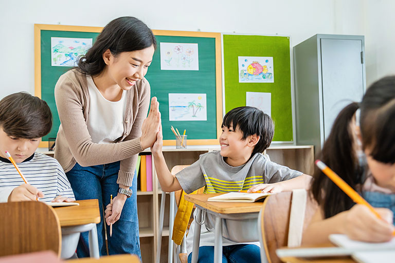 Teacher high-fiving a student in the classroom