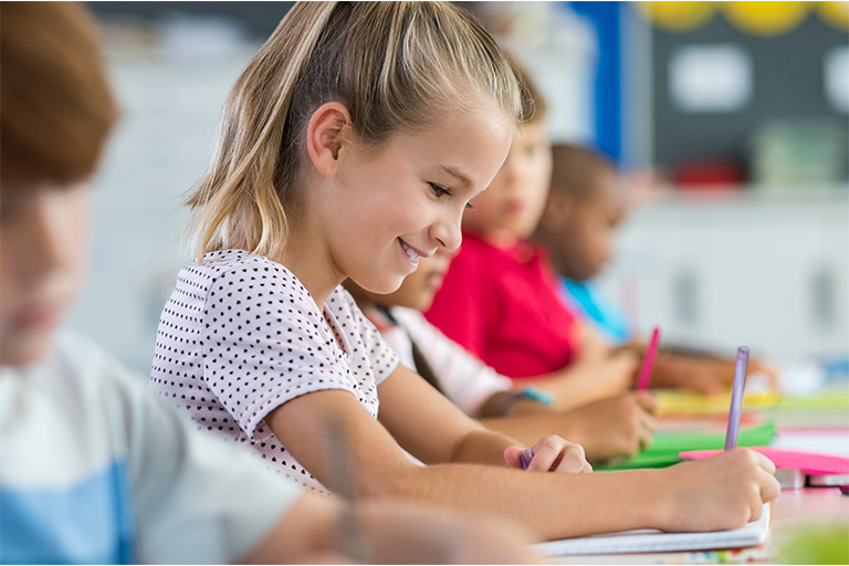 Girl with a smile on her face, working at her desk.